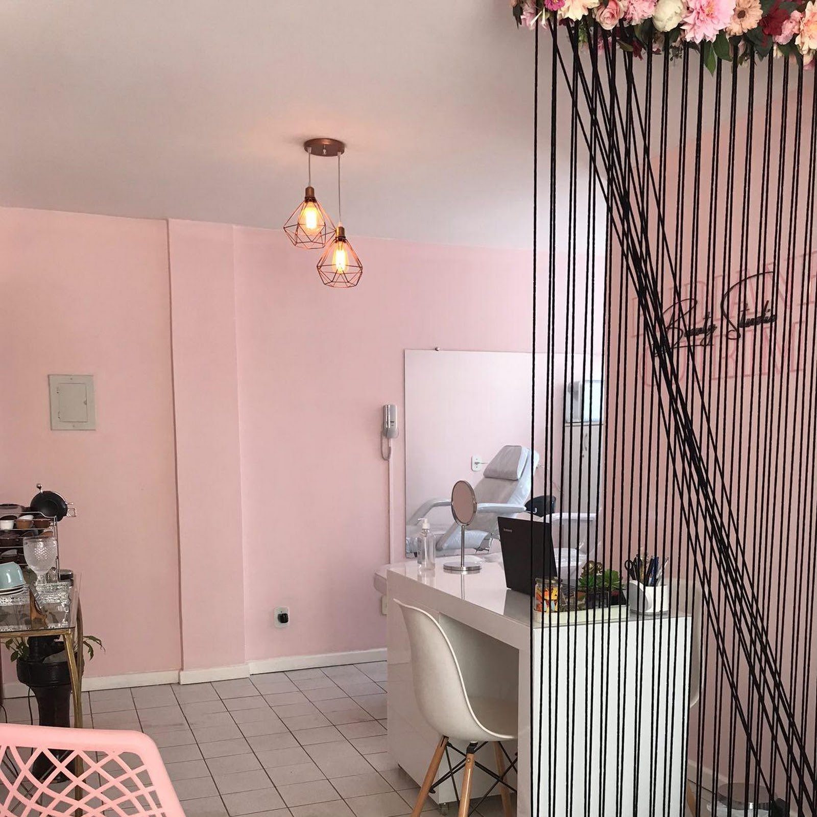 Sala de atendimento em tons de rosa com divisória de cordas e flores